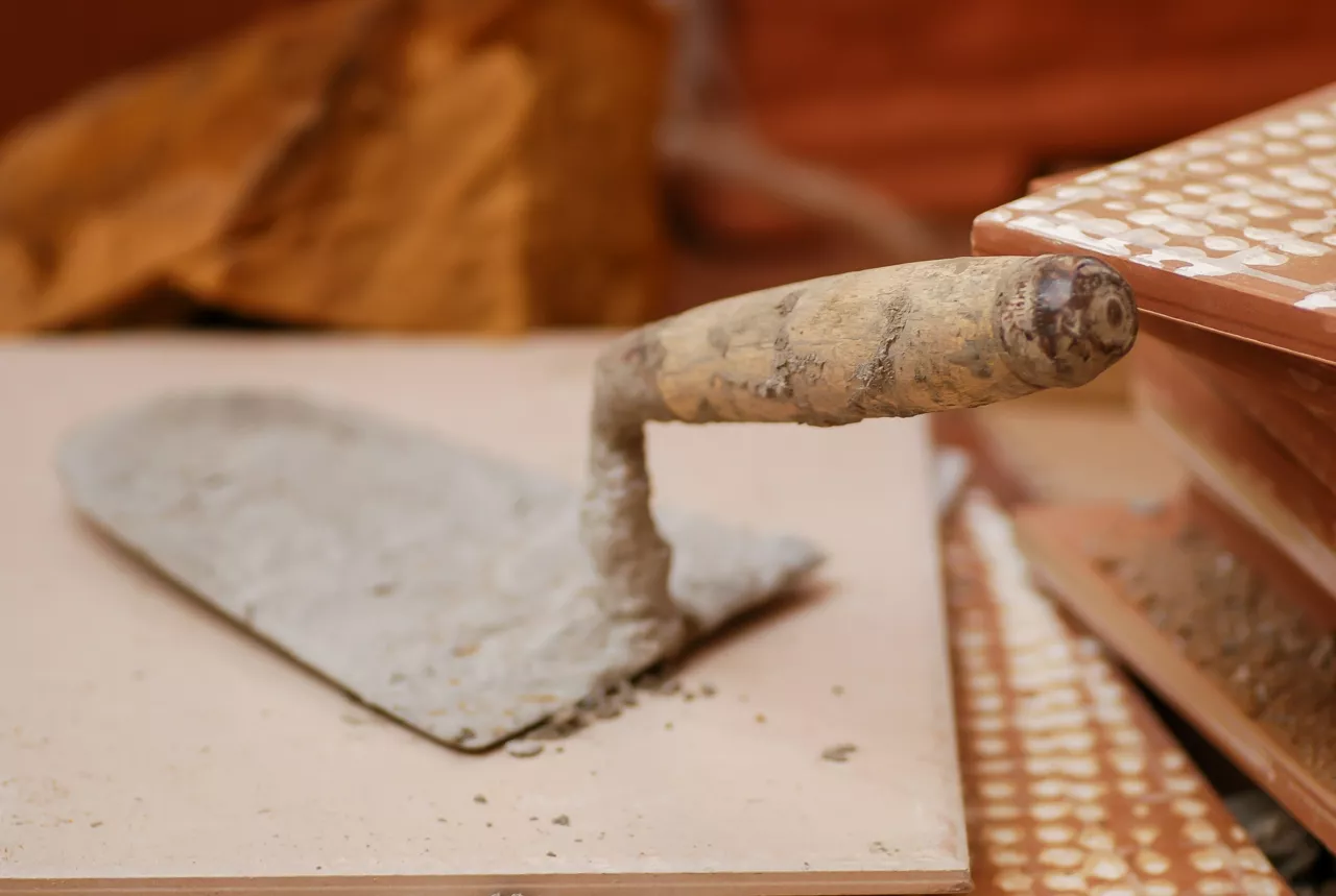 Truelle et béton, prête à être employée par un maçon protégé par la meilleure garantie décennale