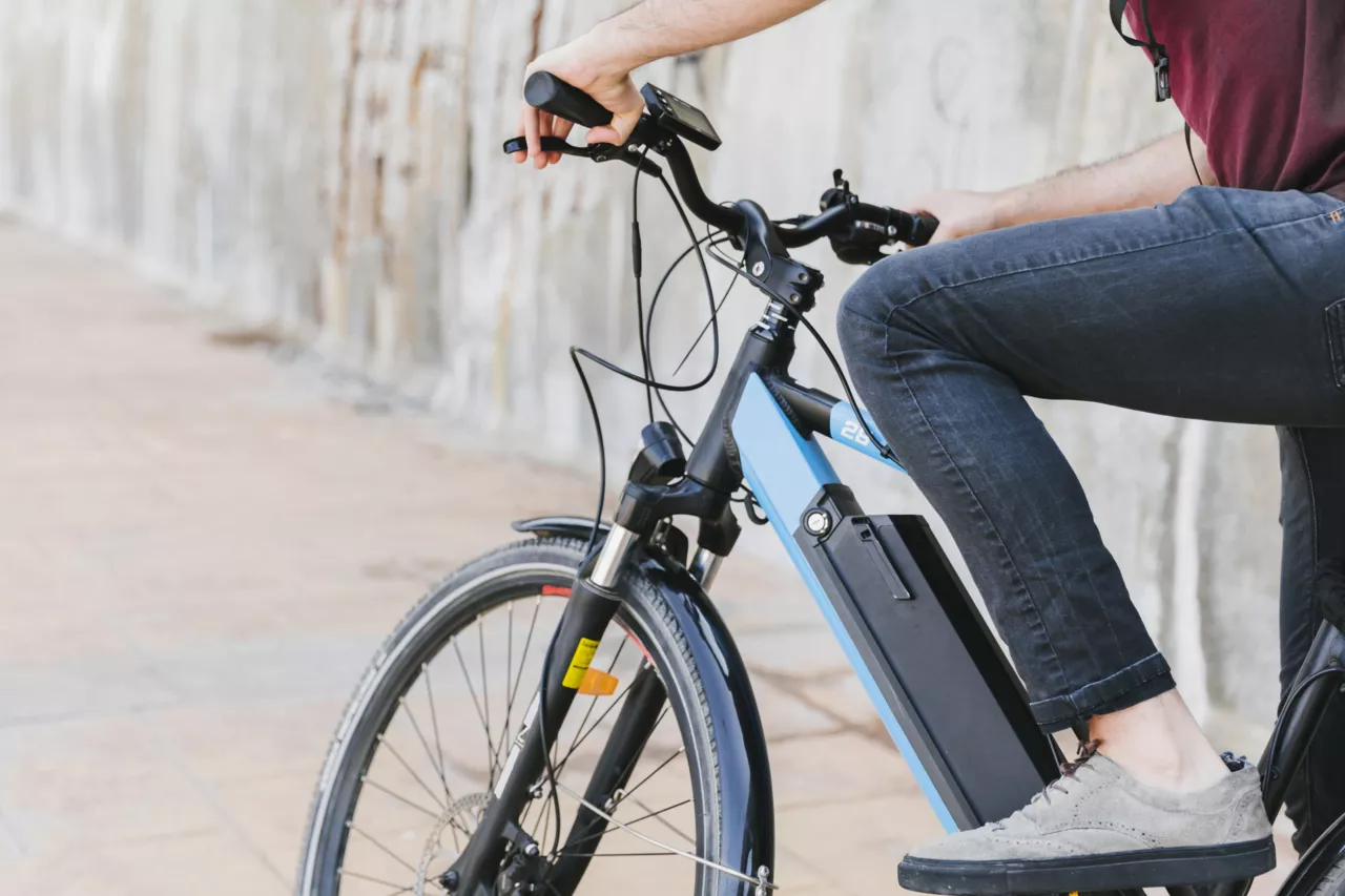 Personne assise sur un vélo électrique bleu et noir, gros plan sur le côté.